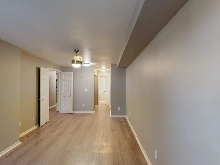 Spacious apartment bedroom with attached bathroom and wood-style flooring.