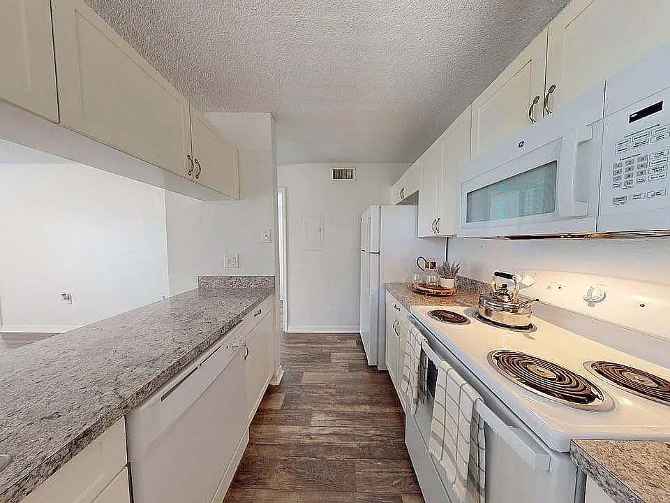 Modern kitchen with sleek countertops, white cabinetry, and contemporary appliances exuding elegance and functionality.