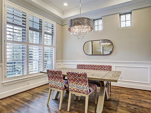 Formal dining room features expansive windows with Plantation shutters, an elegant chandelier, decorative wainscoting panels, and access to a convenient butlerâs pantry.