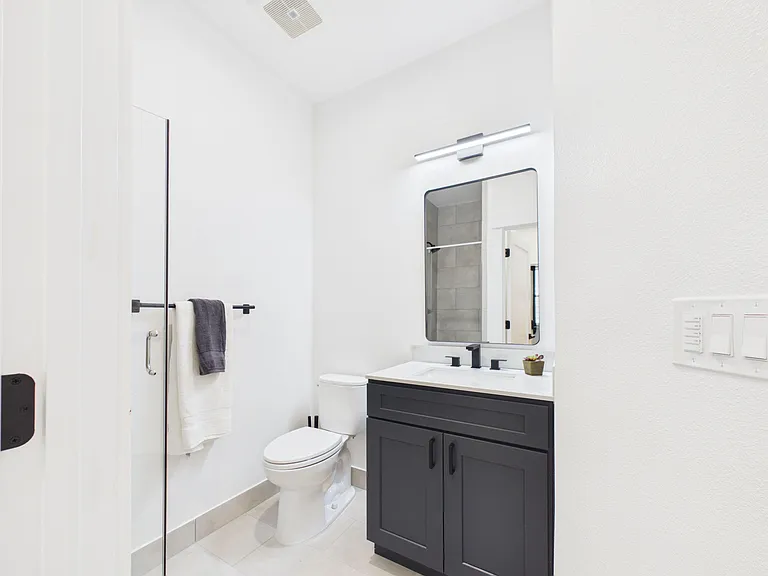 Clean bath with a single-sink vanity, framed mirror, and a walk-in shower with tile surround for easy daily use.