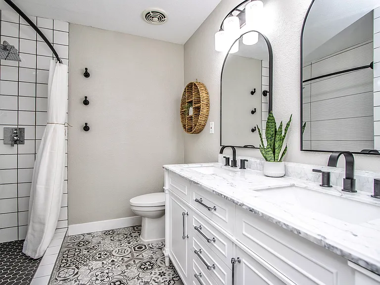 Chic full bathroom at Casa Del Sol, Tempe rental home. Features a double marble vanity, arched mirrors, patterned floor tile, matte black fixtures, and a walk-in shower with a luxury rain showerhead. Premium amenity for a top Tempe, AZ stay.