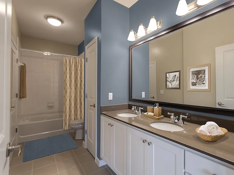 Double vanity bath with quartz stone countertop, white cabinetry and linen closet