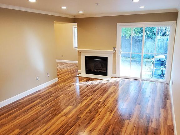 Photo from the front entry across the living room, to the patio access slider and the fireplace adjacent to the dining area.