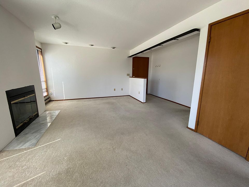 Expansive great room is flooded with natural light and features a classic wood-burning fireplace and large balcony.