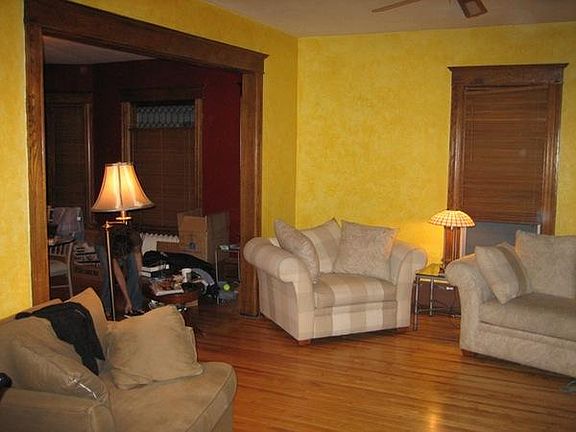 Living room main floor features hardwoods, ceiling fan, leaded glass windows, transom light and wood blinds for privacy.