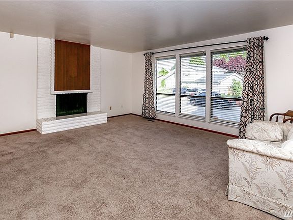 Spacious living room with a wood burning fireplace. Nice neutral paint and carpeting.