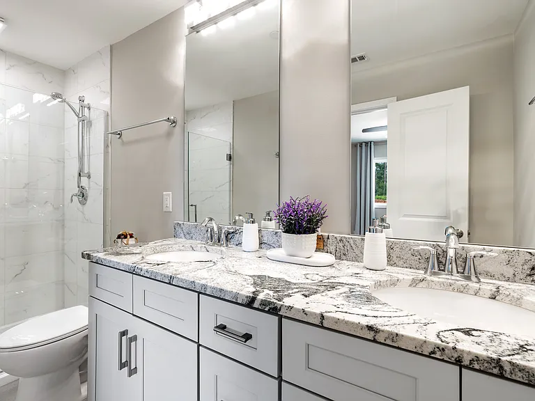 Beautifully designed primary bathroom with dual vanities and a luxurious walk-in shower.