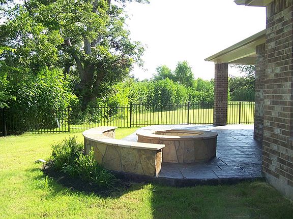Green space and privacy surround firepit and covered patio
