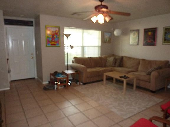View of entry into tiled living area. Lighted ceiling fan.