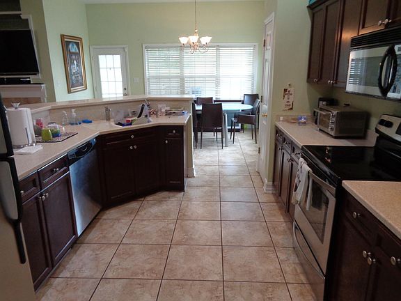 View of the kitchen when entering the house from the garage through the laundry. Matching stainless steel appliances. Easy maintenance tile floors through kitchen and into eating area. Lots of windows and lots of light. Open plan with eating bar for q