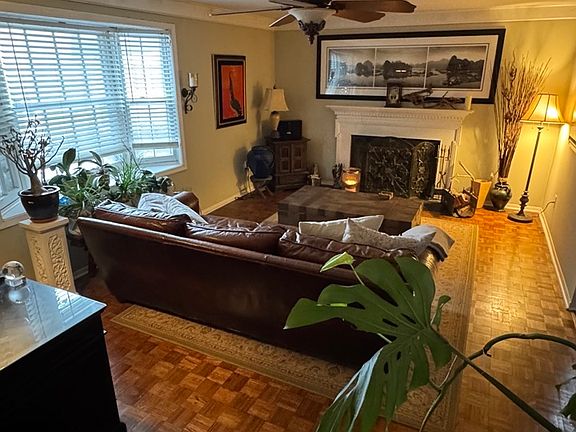 Living room enhanced with a large bay window with natural light and traditional wood burning fireplace.