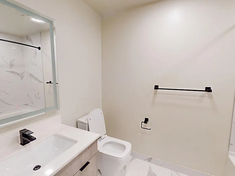 Apartment bathroom with large soaking tub, wood-style flooring, and LED vanity mirror.