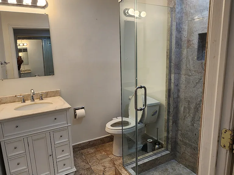 Second bathroom with marble flooring and frameless shower