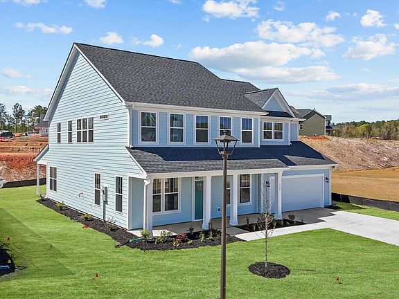 Light blue exterior two story home with centered front door and two car garage at Wells Crossing by