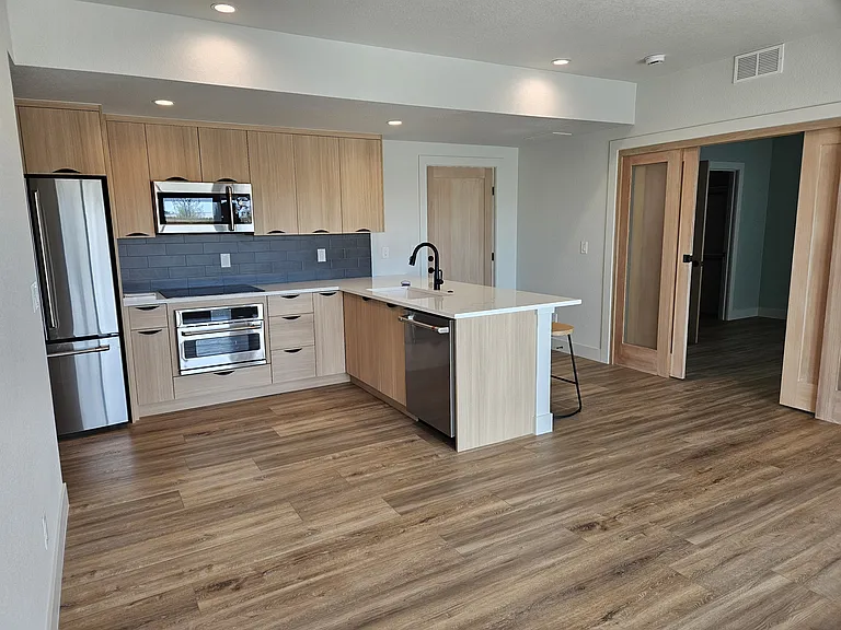 Having entered from the South-side, facing the East rental rooms and the northern door toward the stairway to the garage, there is the common kitchen and appliances and common living room.