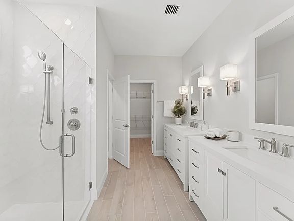 Primary bath with freestanding vanities and glass shower enclosure