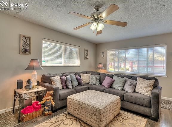 Large main level living room with plenty of natural light. Updated windows, blinds, paint, laminate wood flooring and ceiling fan.
