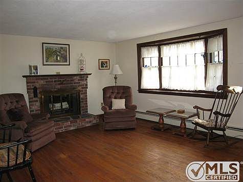 Living room with wood fireplace, Bay window and hardwood floors.