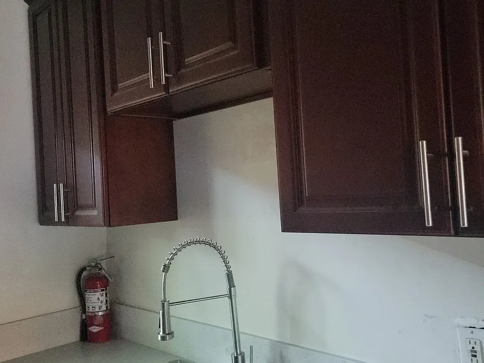 Freshly refinished kitchen including sink counters and cabinets with tile floor.