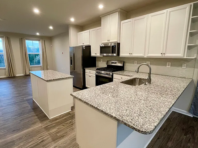 Bright kitchen with ample white cabinets and stainless steel appliances