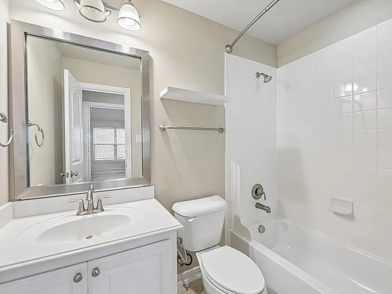 Secondary bathroom. Notice the framed mirror and added shelving.