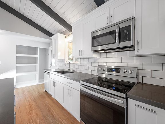 Updated bright & open concept kitchen with quartz counter tops, stainless appliances & vaulted ceilings