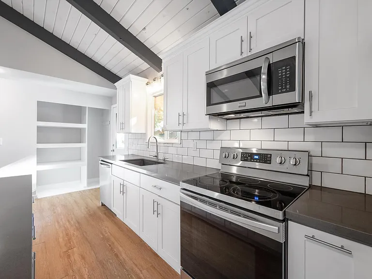 Updated bright & open concept kitchen with quartz counter tops, stainless appliances & vaulted ceilings