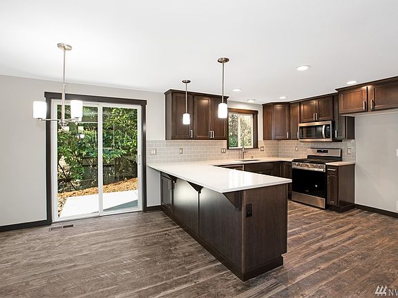 Dining area & gorgeous kitchen. All new cabinets, Quartz tops, SS Appliances, lighting package, laminate flooring. Slider leading to the back patio and private back yard