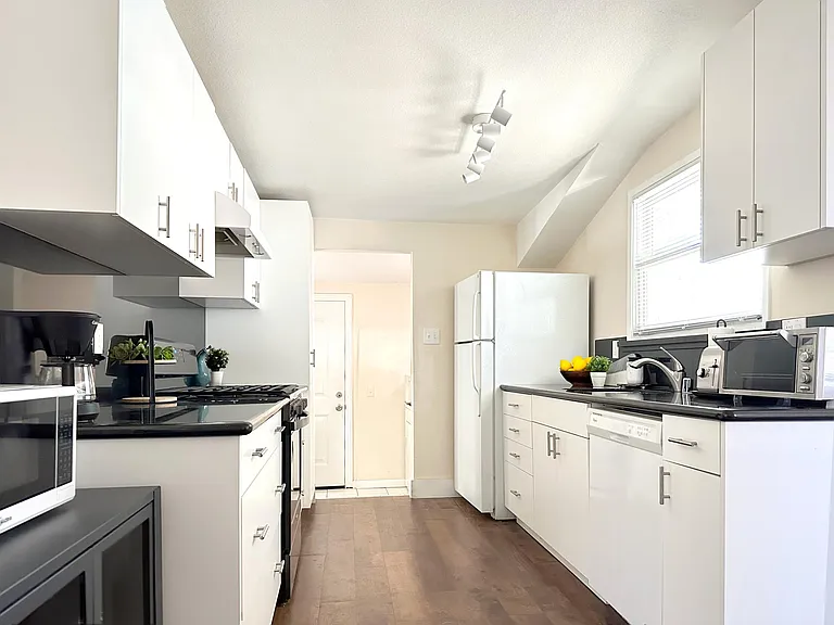 This fully stocked white modern kitchen with black quartz countertops makes the perfect location for cooking at home