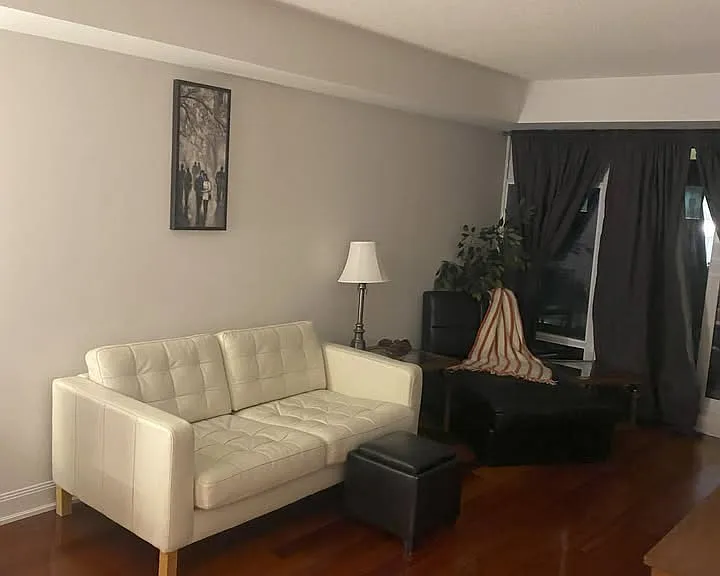 Living room space at one side leading to glassed wall and sliding door to balcony. Leather Loveseat, Chaise Lounge and end table