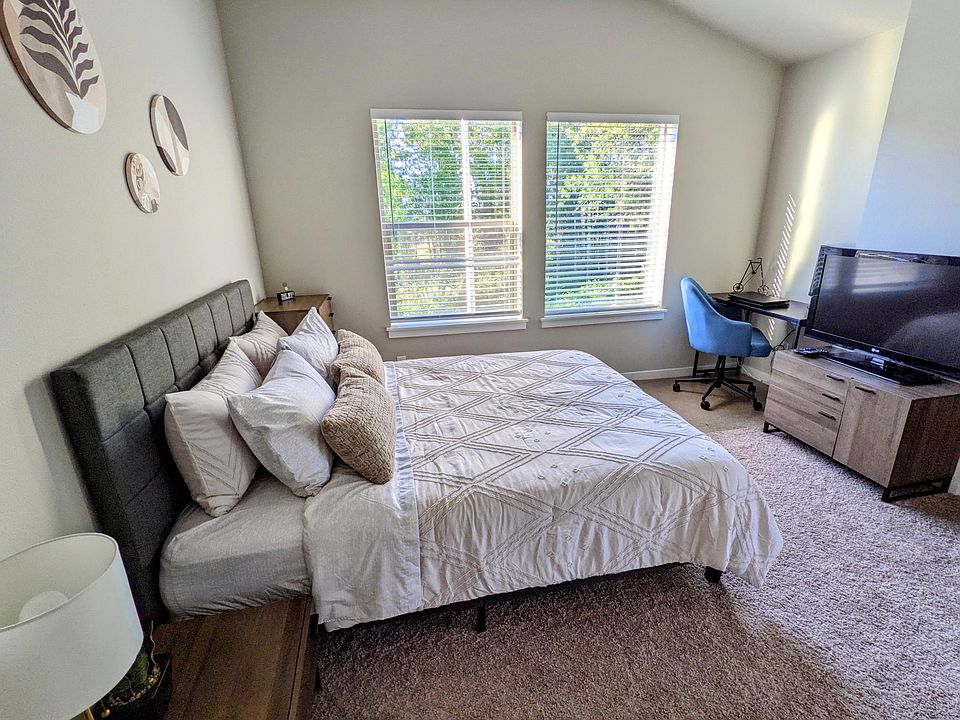 Second bedroom with vaulted ceiling, large windows, and flexible space for bedroom or home office.