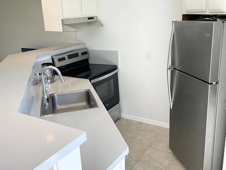 Kitchen with new stainless steel appliances. Whirlpool fridge and oven. GE dishwasher. Broan ducted hood range.
