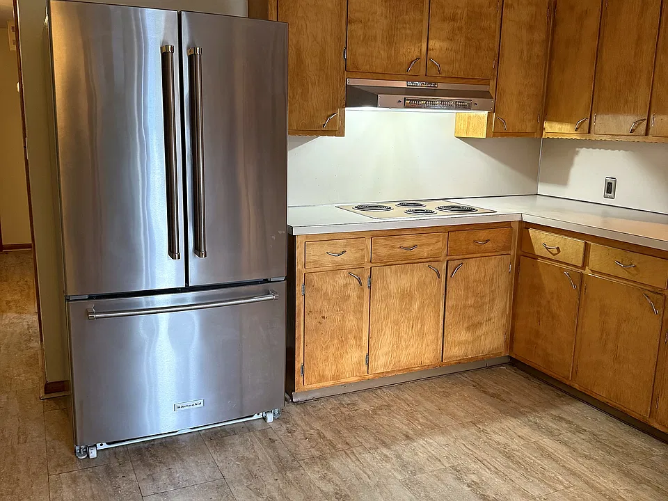 A big, bright kitchen with original maple cabinets and a stainless French-door refrigerator.