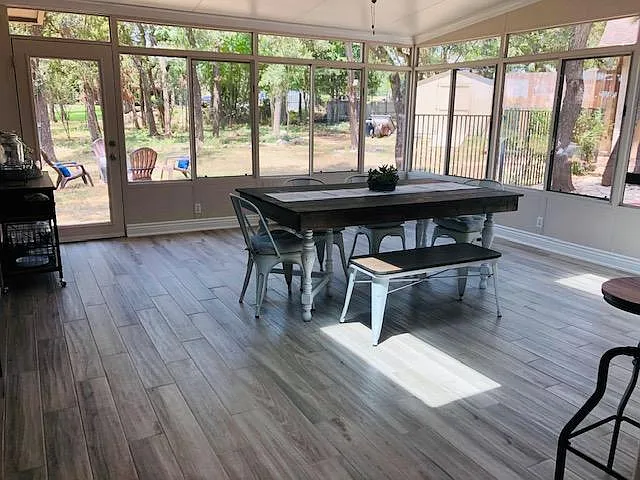 The dining room is surrounded by sunroom windows.