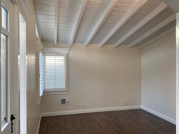 Large and aire open beam ceilinging living room featuring large windows and plantation shutters letting in ocean breazes and sunlight!