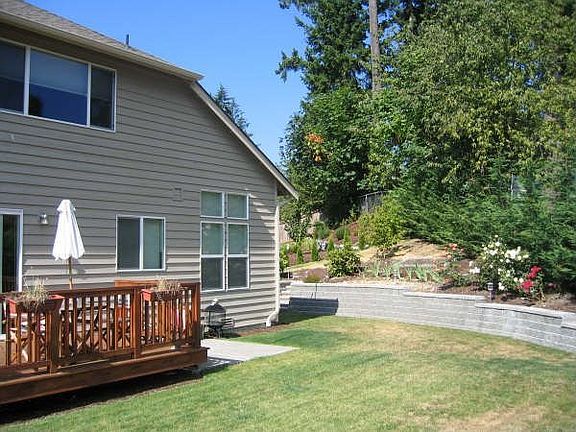 Beautifully landscaped backyard with gorgeous retaining walls, trees and lawn.