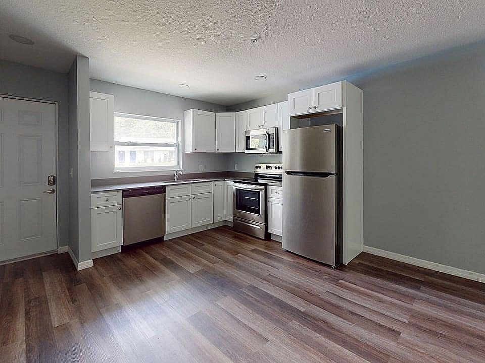 Modern kitchen with sleek stainless steel appliances, elegant white cabinetry, and warm wood flooring, offering an inviting and functional cooking space.