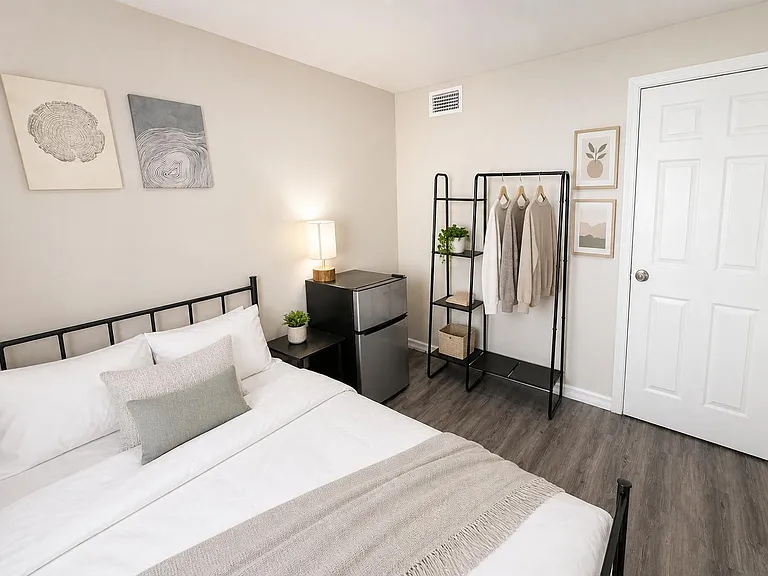 Move-in-ready bedroom with full bed, open wardrobe, mirror, and cozy modern charm