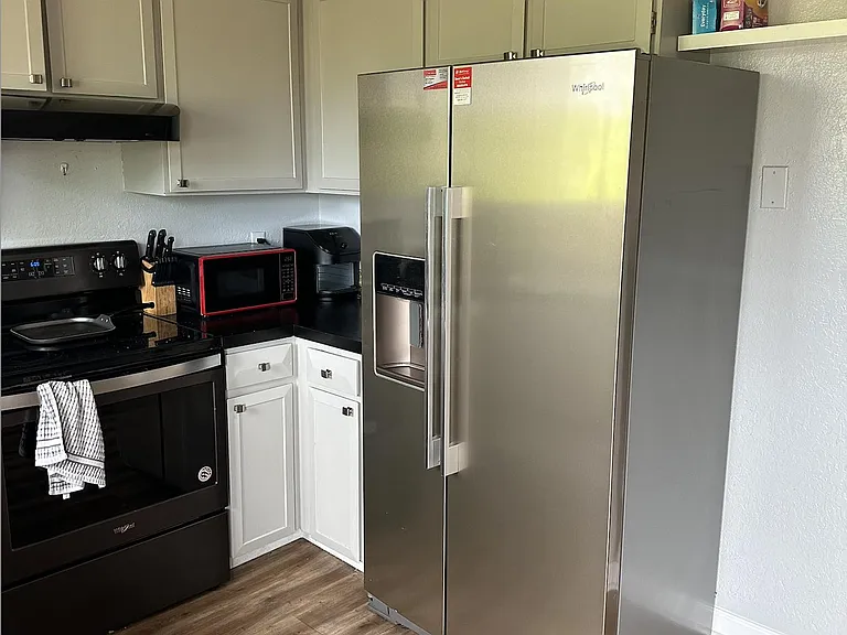 Kitchen features ample cabinetry, durable counters, and a full appliance set including range and side-by-side refrigerator.