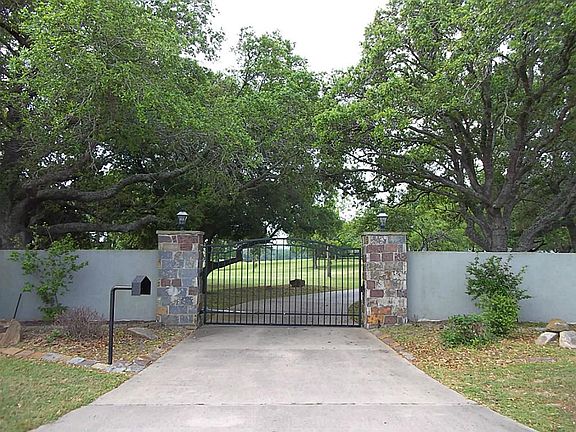 Gated entrance with driveway curving through live oaks