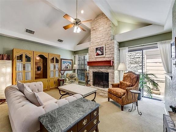 Light filled living room with vaulted ceilings, recessed lighting, native stone fireplace and wet bar.