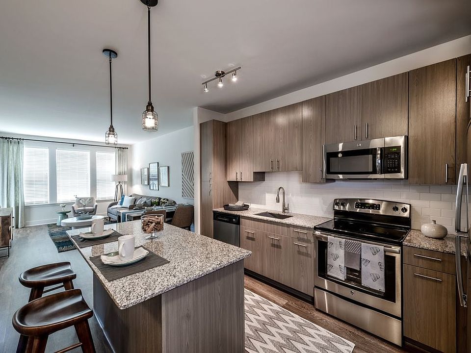 Open concept kitchen with brown cabinetry, granite countertops, kitchen island, stainless steel appliances, tile backsplash and hard surface flooring