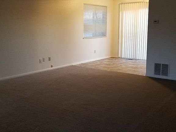 From front door, across living room towards dining and kitchen. Fireplace just to left of door, and stairs on right out of frame.