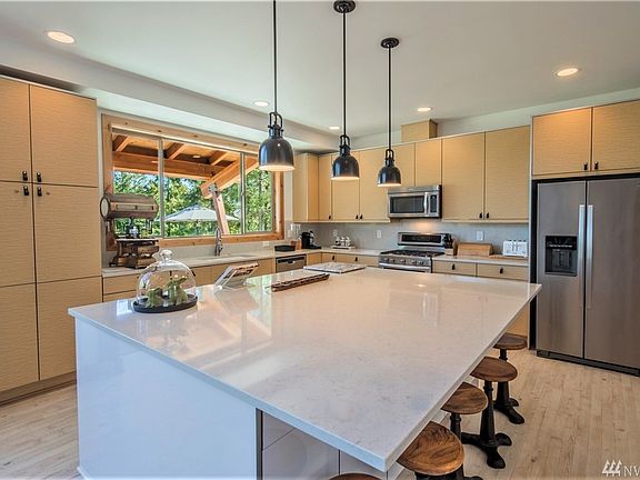 The oversized custom kitchen island with quartz countertop and eating bar is a central gathering spot which generates as much love and laughter as it does fine food.