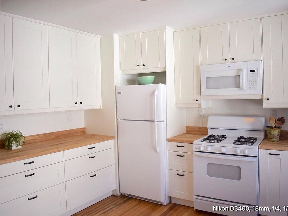 Eat-in kitchen with gas range, refrigerator, shaker cabinets, butcher block counters.