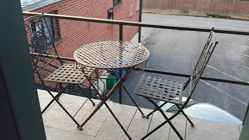 REAR metal deck overlooking parking lot, with seasonal use of tile and metal table and two chairs for apt use