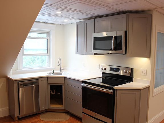 Partial view of kitchen area w/ window,quartz counters s.s. stove , microwave , large sink w/ disposal and dishwasher