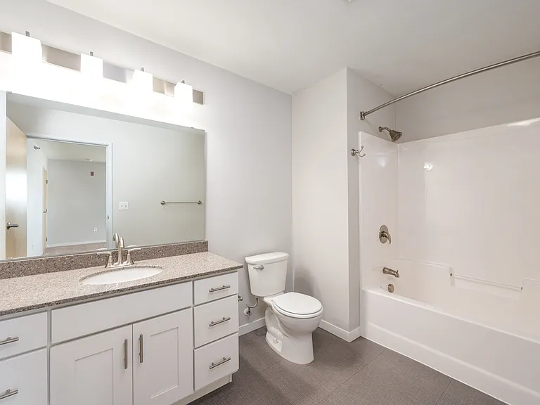 Modern bathroom featuring sleek white cabinetry, a spacious mirror, and a pristine bathtub with stylish fixtures. Modern bathroom featuring sleek white cabinetry, a spacious mirror, and a pristine bathtub with stylish fixtures.