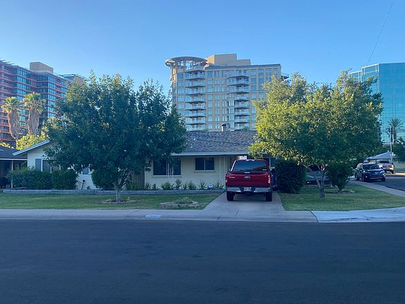 Front of the house. View from Elm St. Large trees provide shade for the driveway. Carport is behind the truck.