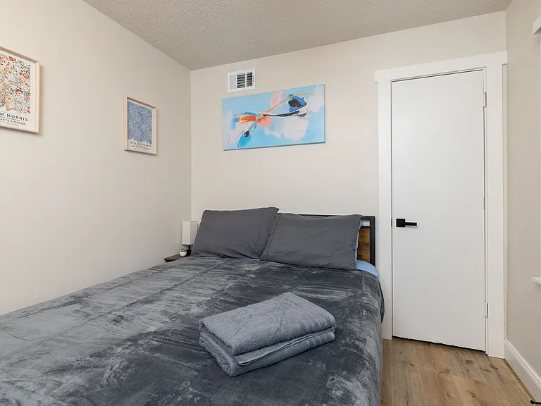 A simple, comfortable bedroom ideal for peaceful rest, complete with fresh linens and soothing artwork. Minimalist, clean, and perfect for a quiet night's sleep.